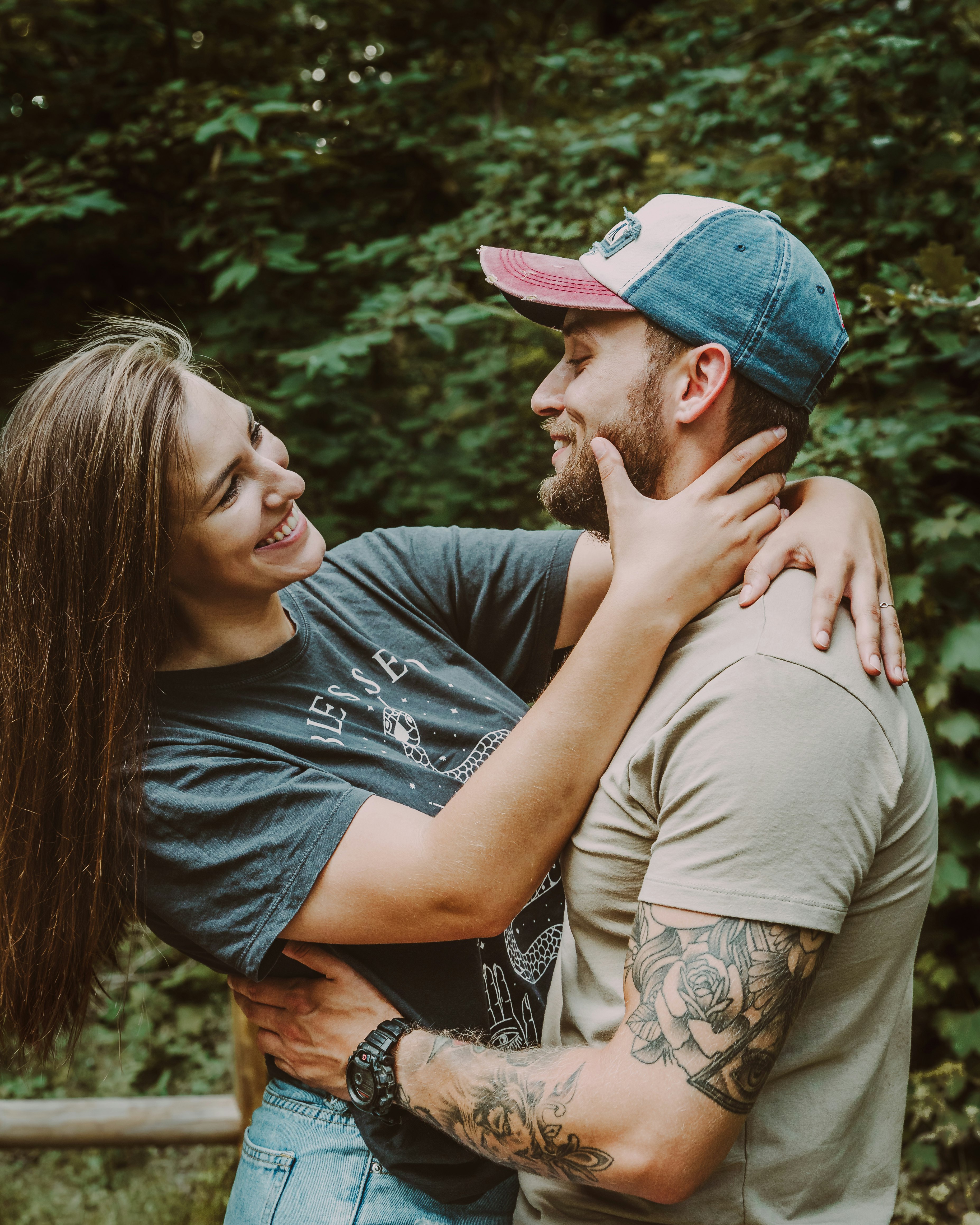 man in gray crew neck t-shirt kissing woman in blue denim cap